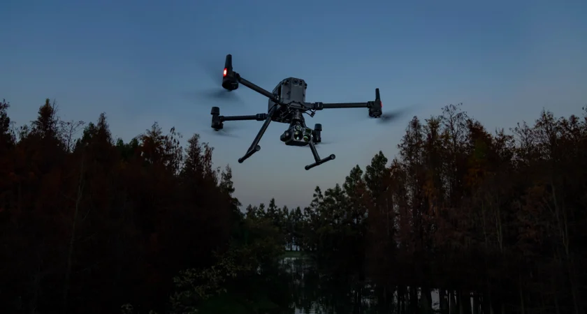 A giant drone in a forest evening sky
