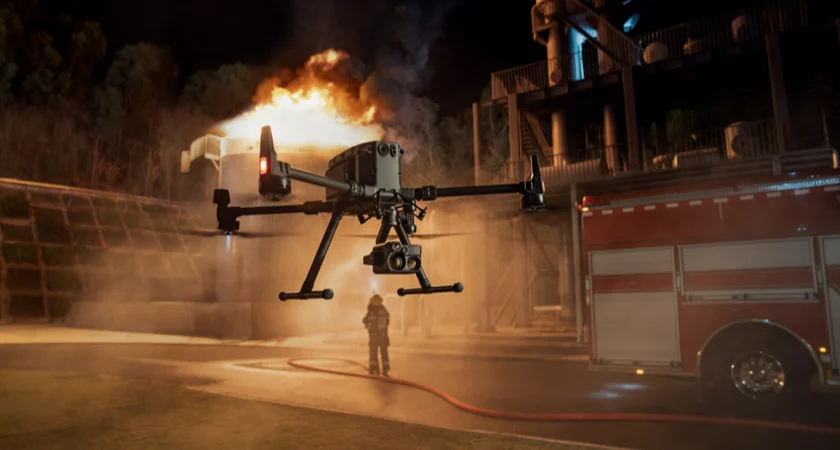 A night vision drone hovering above air beside a firetruck