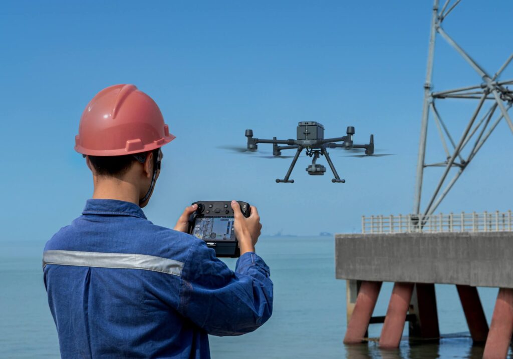 A backview of an engineer operating a long range drone above sea industrial area