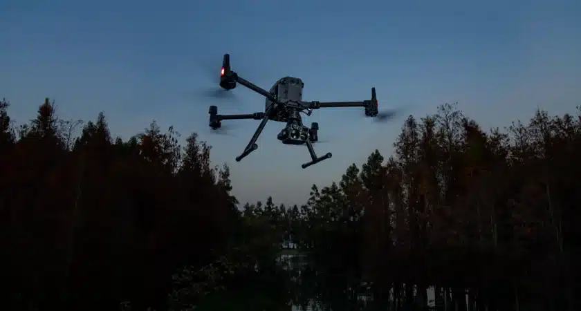 A giant drone in a forest evening sky