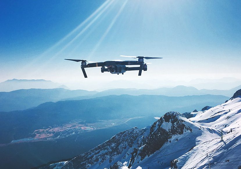 A long range drone showing its range flying high in the sky over snowy mountains
