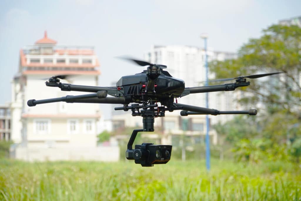 A night vision drone hovering above the grass during day time