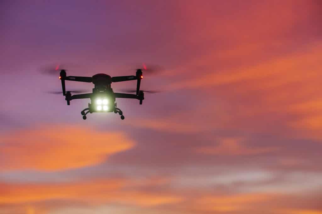 A night vision drone with lights flying in the orange sky