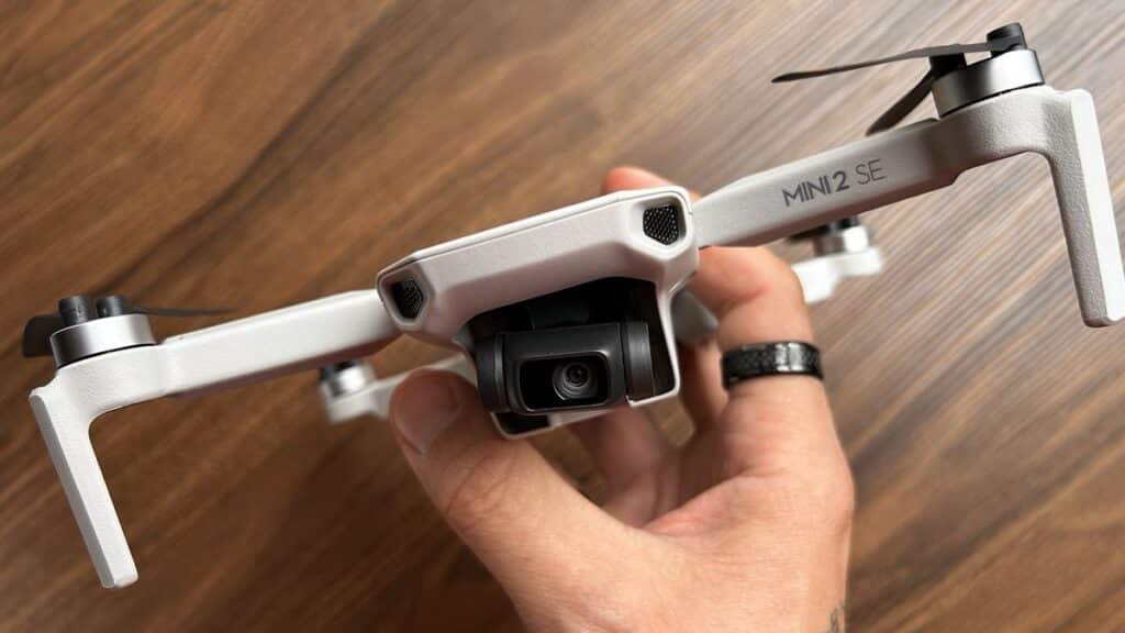 a person holding DJI mini SE on wooden smooth surface