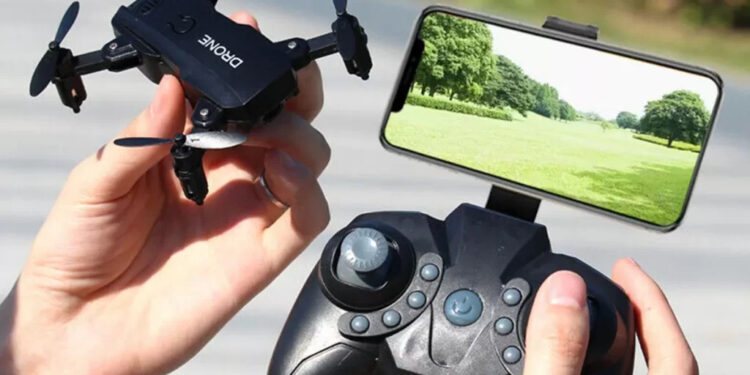 a person holding remote controller attached to a smart phone in one hand mini drone in other