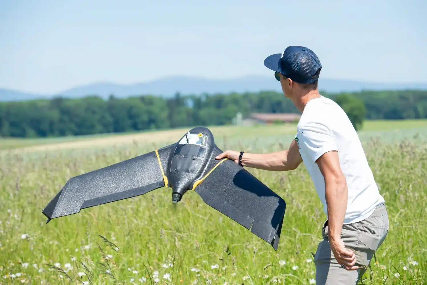 a person holding sensefly bee drone in a field