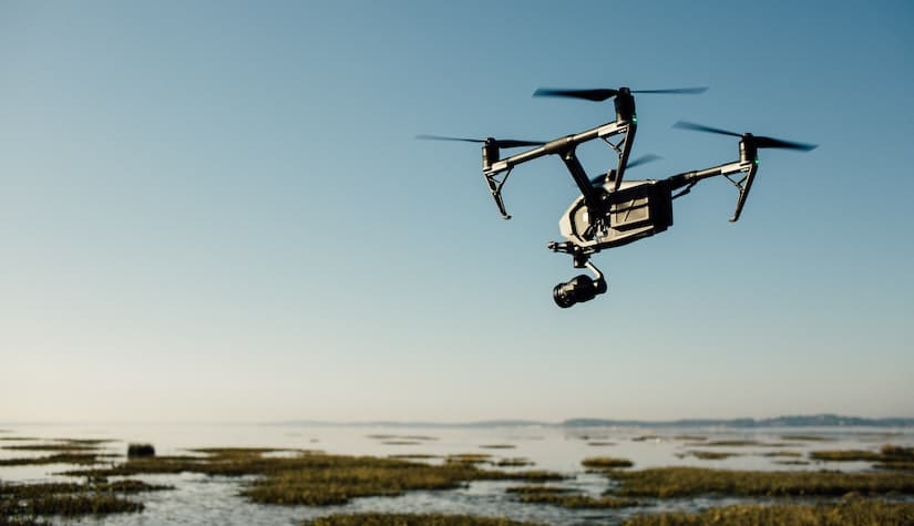 black drone taking aerial shots in a field