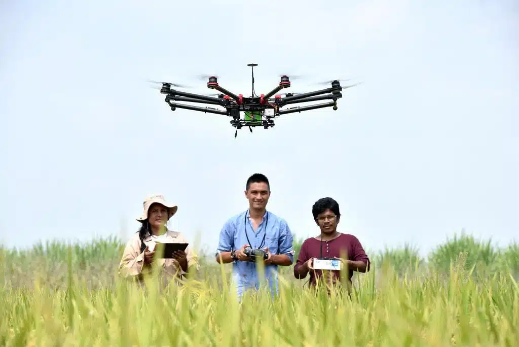 one man and women standing in a field and operating drones