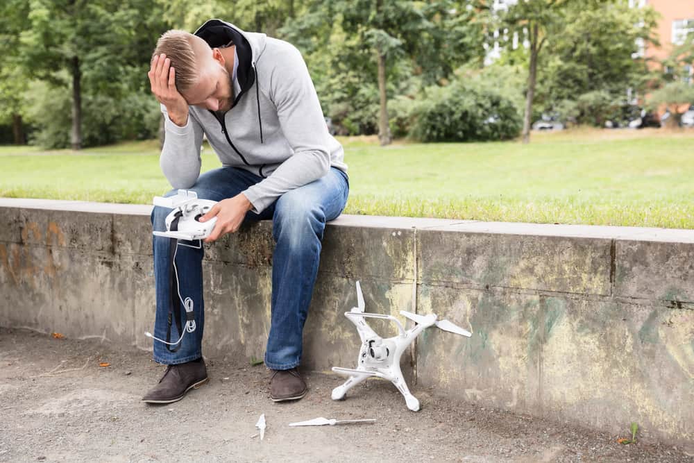 A view of a person sitting with a head over his head and holding a broken drone remote