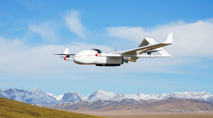 A view of a white gas drone hovering over mountains