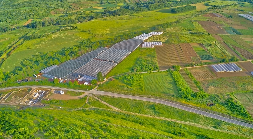 Green Agricultural Fields With Various Crops And Greenhouses views from drone in a sunny day 